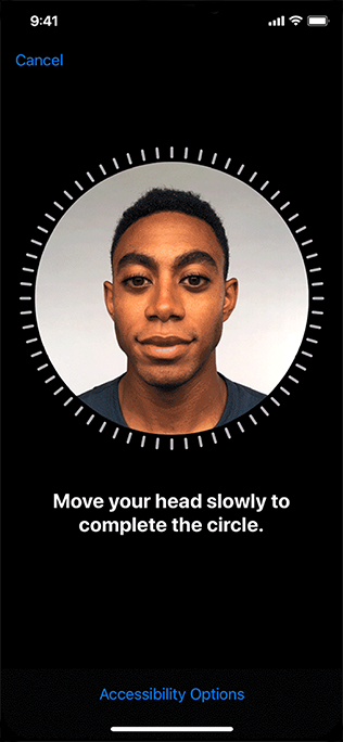 A screenshot of the Face ID setup screen on iPhone. A man's face appears inside the circular frame and the white tick marks around the frame show that he hasn't started moving his head yet. The text below the frame reads Move your head slowly to complete the circle.